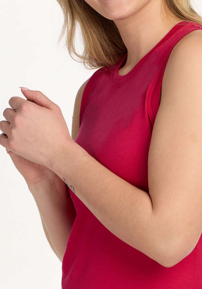 Wearing the Woolx Bella Tunic Top in Poppy Spark, a person stands against a white background with hands clasped, their face partially visible.