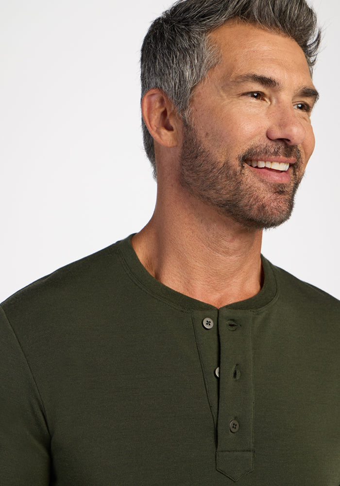 Smiling man with gray hair and beard wears Woolx Jackson Henley - Duffel Bag shirt against a plain background.