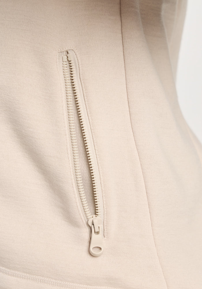 Close-up of a zippered pocket on an ecru Woolx Cubby Hooded Sweatshirt in warm fleece.