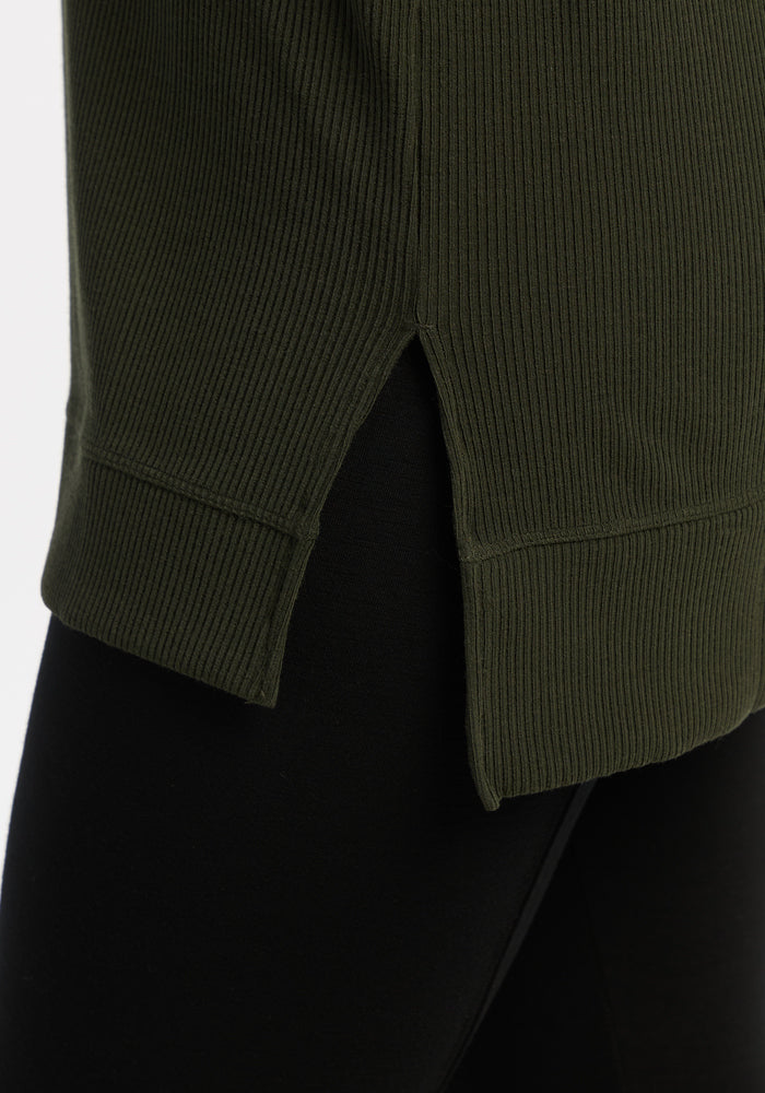 Close-up of the Woolx Evie Ribbed Tunic - Duffel Bag, a warm women’s top with side slit, layered over black leggings.