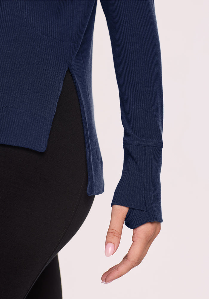 Someone in a Woolx Ainsley Sweater - Ocean Cavern and black leggings, hand relaxed at their side.