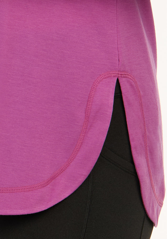 Close-up of the side of the Woolx Hazel Tunic in Purple Wine, featuring a curved hem and small side slit, styled over black leggings.