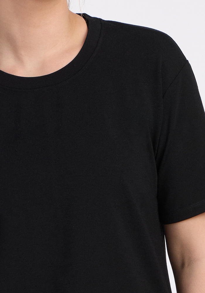 Close-up of a person wearing the Woolx Audrey Tee in black, showing only the neck, shoulder, and upper chest against a plain light background.