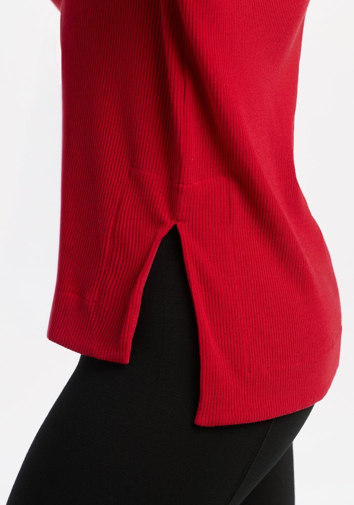 Close-up of a person in the Woolx Ainsley Sweater - Maraschino Cherry, styled with black pants.