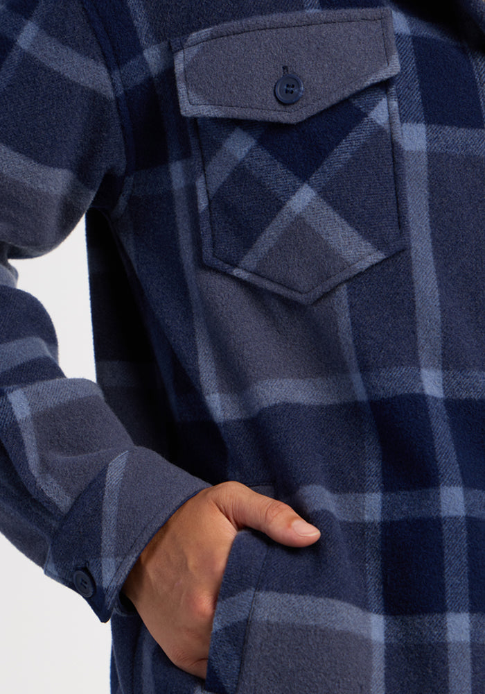 She wears Woolx’s Sawyer Shacket—Midnight Harbor Plaid, a women’s blue plaid oversized shacket, hand in pocket.