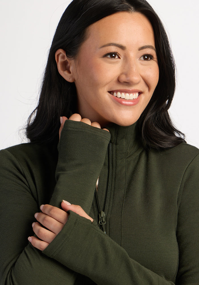 Woman with long dark hair smiles in a Woolx Finley Zip Up Sweatshirt - Duffel Bag, on a white background.