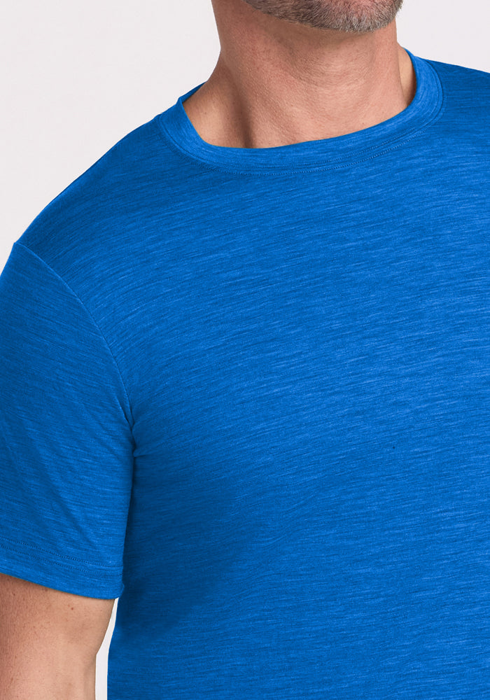A man wearing the Woolx Endurance Tee in Glacial Blue, a short-sleeve Merino wool crew neck shirt, is shown from shoulders to mid-torso with his head partially out of frame.