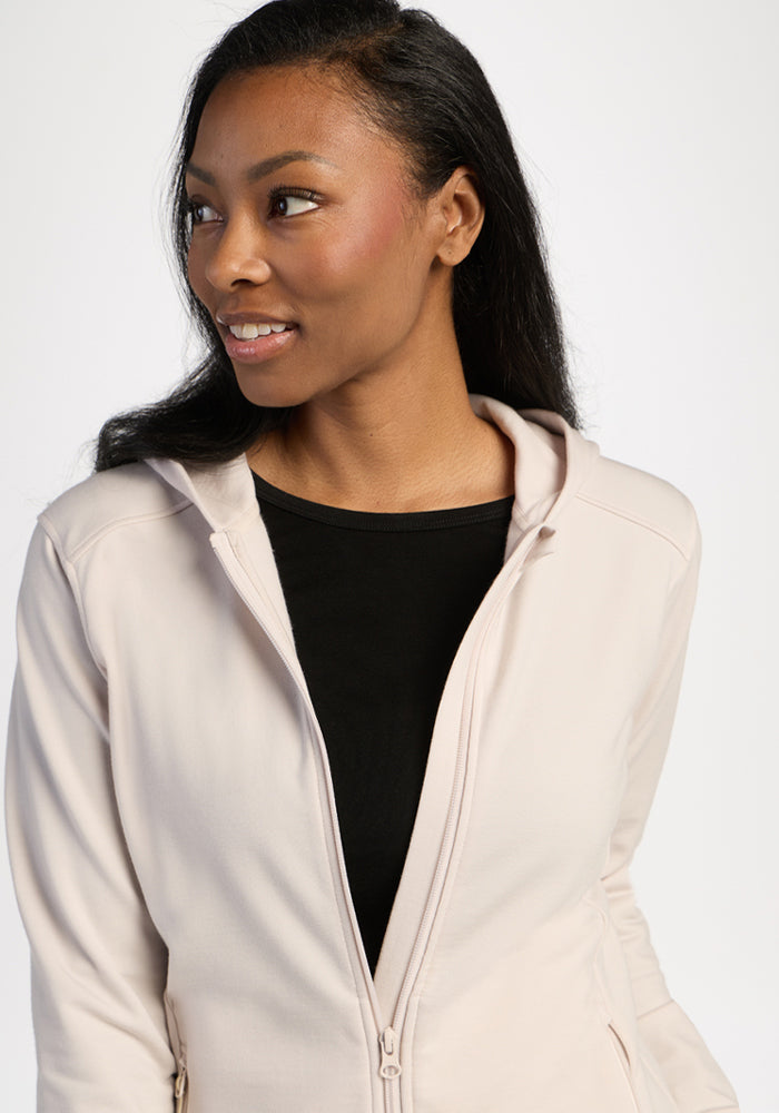 Woman in a Woolx Darby Zip Up Hoodie - Ecru over a black shirt, looking to the side against a neutral background.