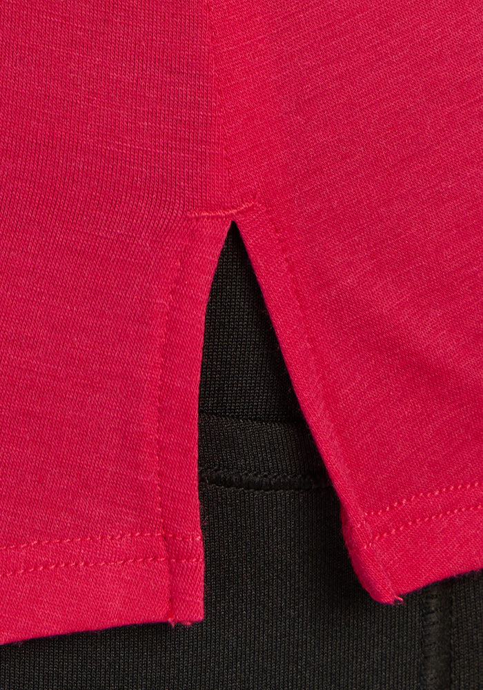 Close-up of the Bella Tunic Top in Poppy Spark by Woolx, layered over black pants and paired with a lightweight merino tank for effortless summer style.