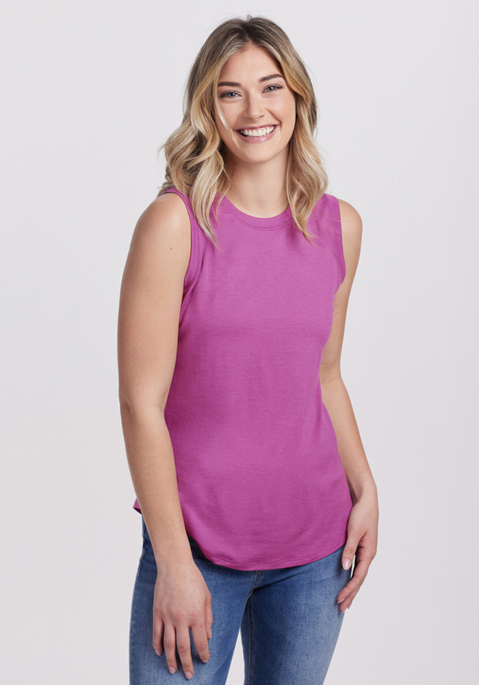 A smiling blonde woman wears the Woolx Bella Tunic Top in Purple Wine and blue jeans, standing against a plain light background. 
