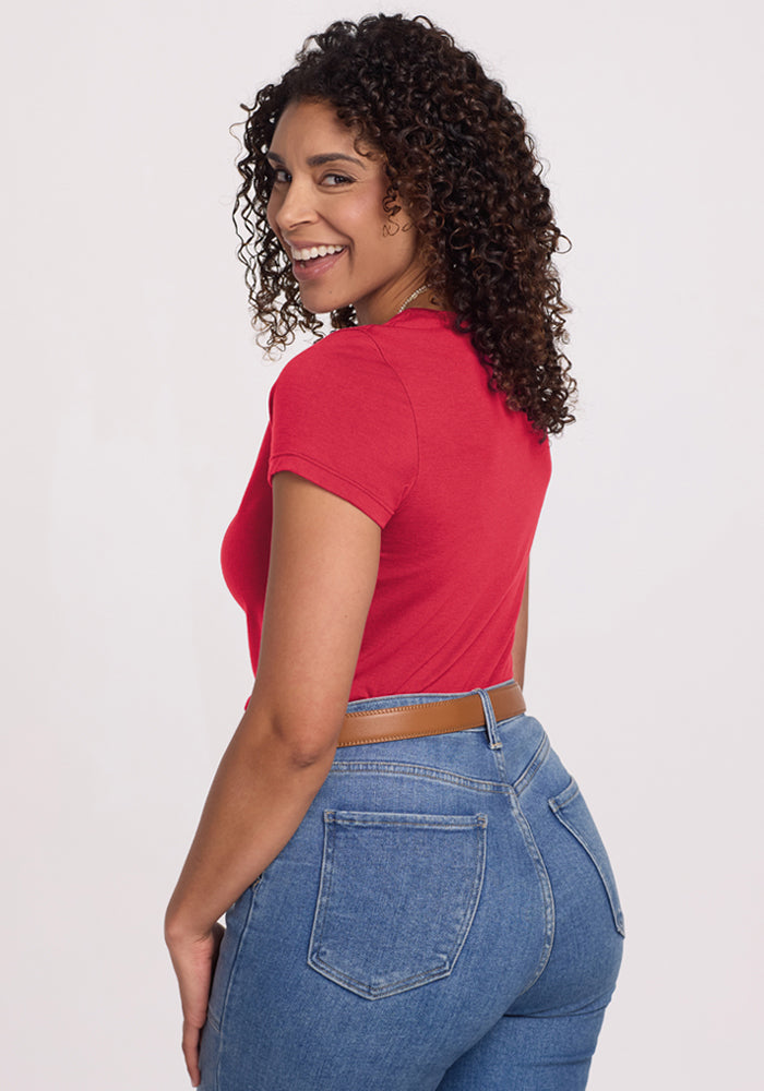 Woman with curly hair smiles over her shoulder in the Woolx Addie Crew Neck - Berry Ice Pop against a light background.