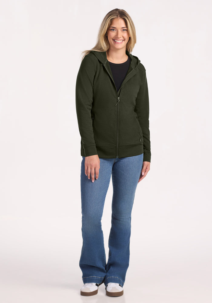 Woman in Woolx Darby Zip Up Hoodie - Duffel Bag, blue jeans & white shoes, poses by a plain light background.