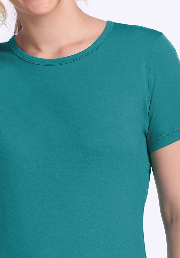 A close-up of a person wearing the Woolx Liza Crew Neck Tee - Surfside, highlighting the upper chest, shoulder, and part of the face against a plain light background.