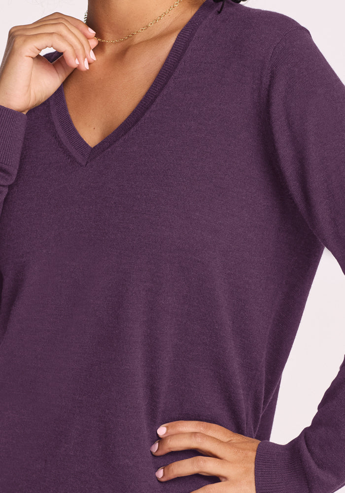Woman in Woolx Francesca Sweater - Purple Iris, one hand near face, the other resting on her hip.