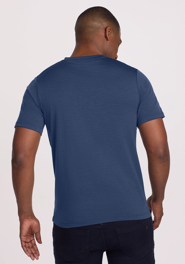 A man stands with his back to the camera, wearing the Woolx Endurance Tee in Starry Night and dark jeans, set against a light background.