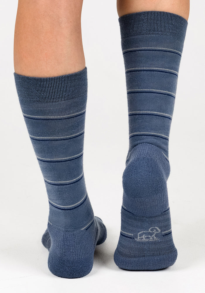 The Woolx Womens Chandler Mid Calf Sock in Vintage Indigo, featuring thin white stripes and a small cloud detail on the heel, is shown worn from the back against a plain white background.