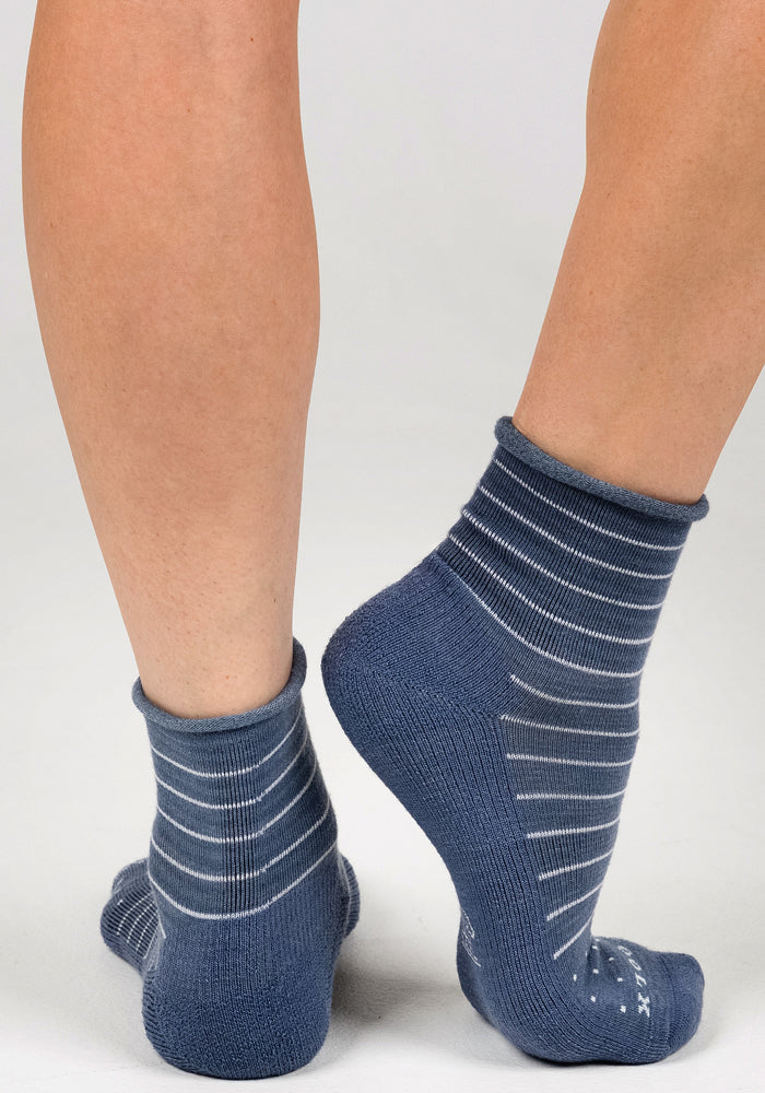A person models the Woolx Womens Derby Roll Top Sock in Vintage Indigo, featuring white horizontal stripes, standing on tiptoe to display the back and side of their legs against a plain light background.