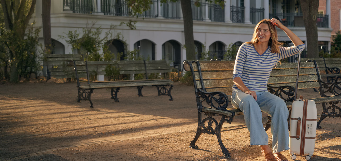 Woman wearing blue sand elena stripe top sitting on bench
