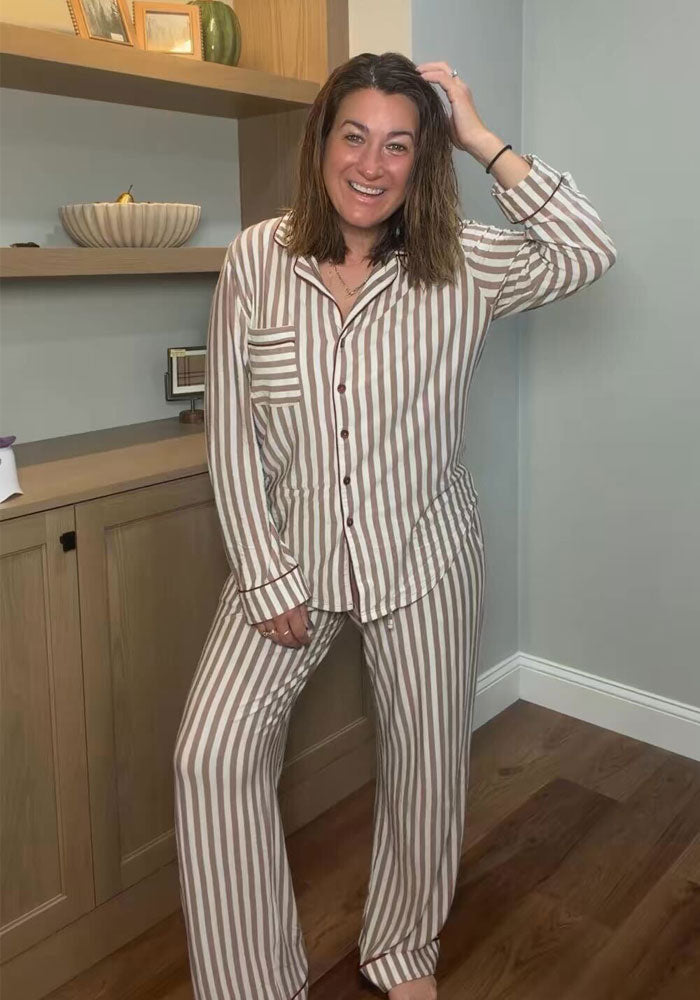 Woman in a tan and white vertical-striped Harper FeatherTouch® Pajama Set, a long-sleeved, button-down, moisture-wicking top.