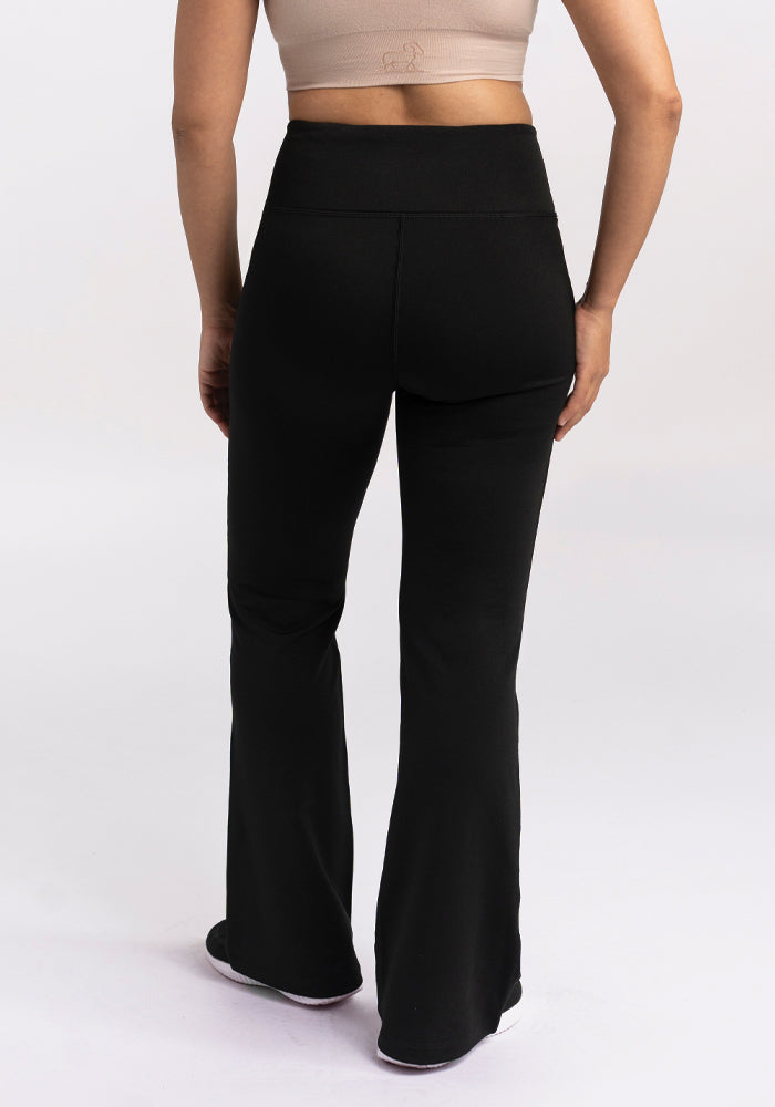 Person wears Woolx Marissa Tall Pants in black and a beige crop top, shown from the back against a plain background.