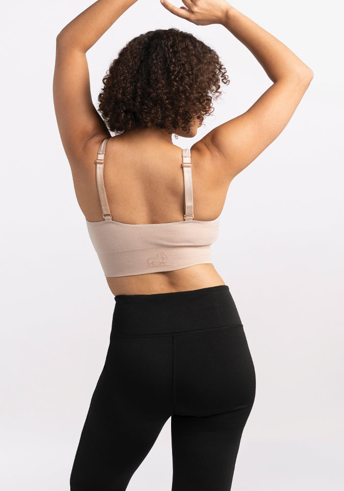 Person with curly hair wearing Woolx Marissa Tall Pants - Black and a beige bra, arms raised, shown from the back.
