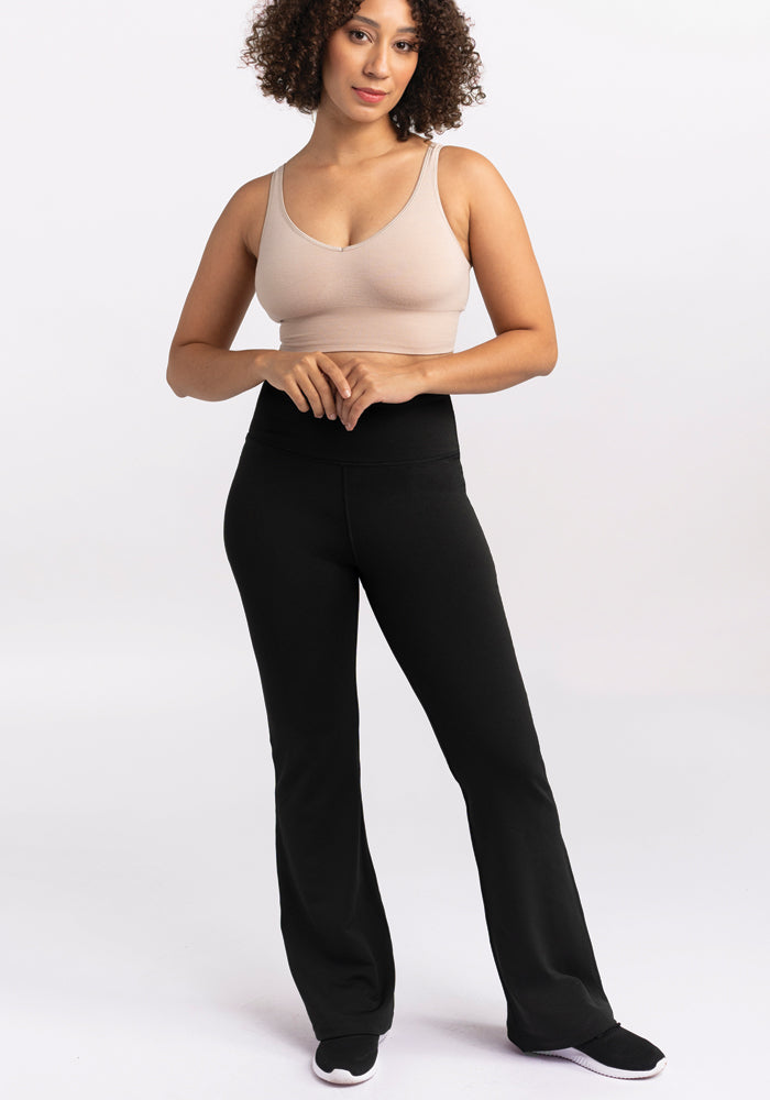 Woman in Woolx Marissa Tall Pants - Black, beige tank top & sneakers, stands against a plain white background.