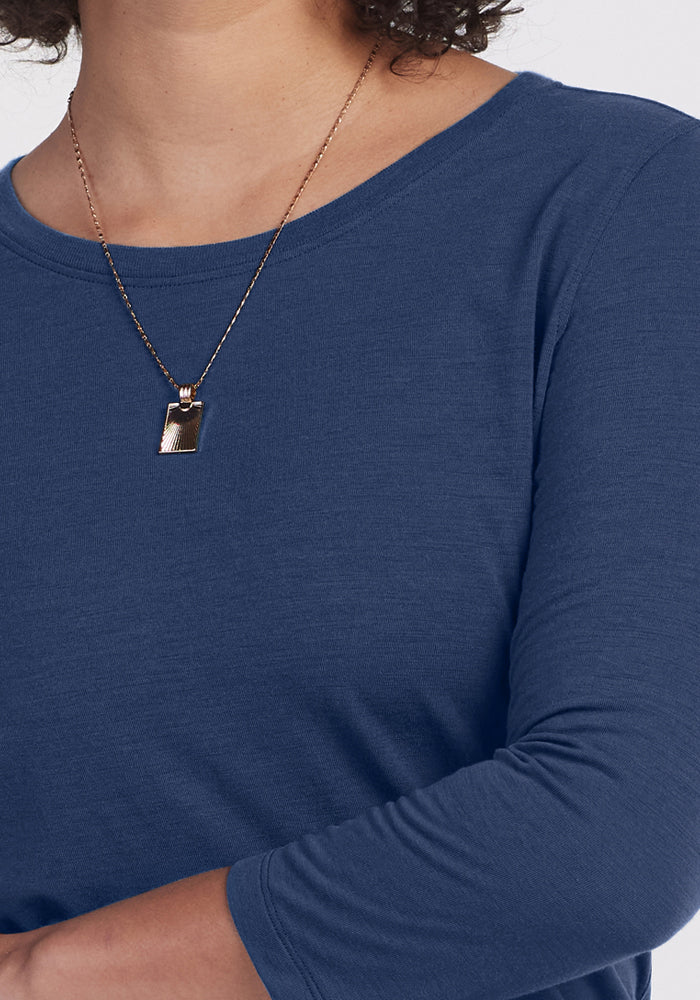 A person wearing the Woolx Jenny 3/4 Sleeve Crew Neck in Starry Night and a gold chain necklace with a rectangular pendant. Only their lower face, neck, and upper torso are visible.