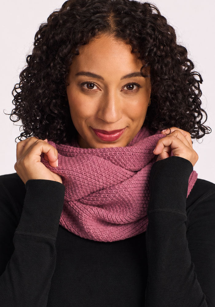 Woman with curly hair smiles at the camera in a Woolx Noelle Infinity Scarf - Toasted Rose and a black top.
