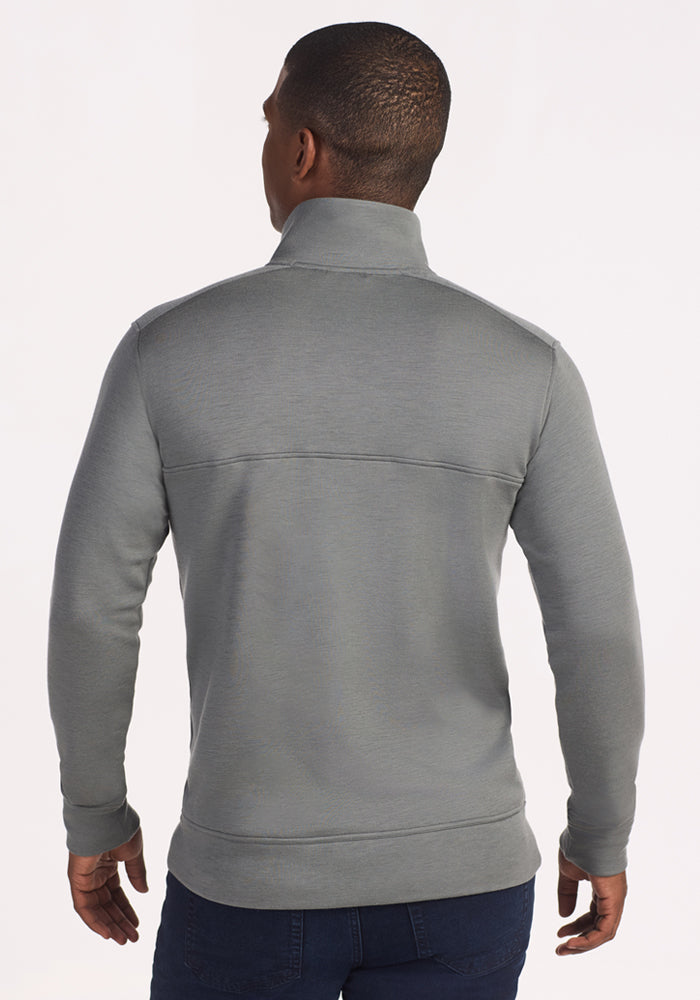 A man faces away from the camera, wearing the Woolx Mason 1/4 Zip in Sedona Sage and dark jeans, set against a plain, light background.