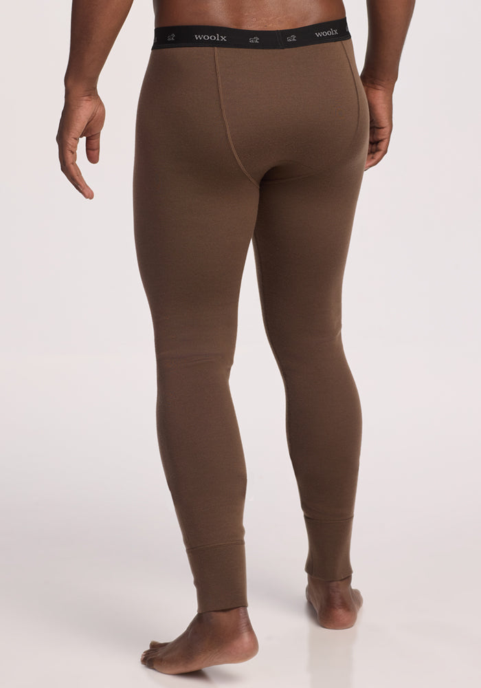 A person is standing barefoot on a white background, shown from the back, wearing Woolx Arctic Leggings in Bourbon Oak with a black waistband.