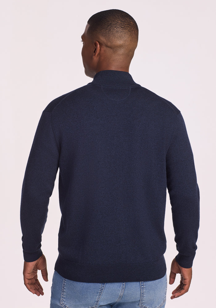 A man wearing the Woolx Enzo Quarter Zip - Storm Cloud sweater and light blue jeans stands with his back to the camera against a plain light background.