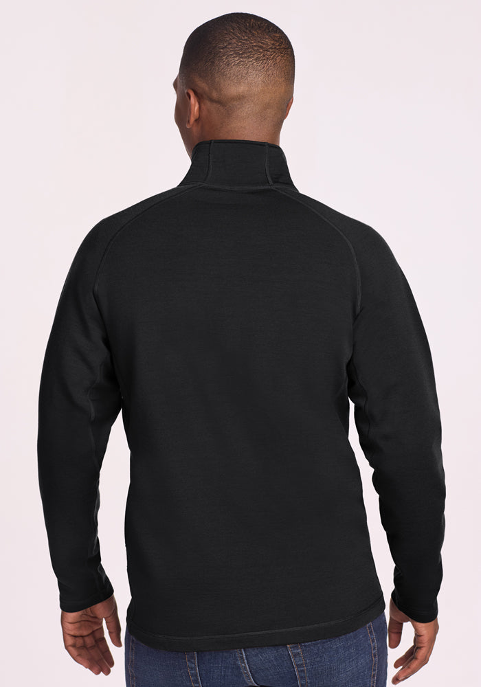 A man is seen from behind wearing the Woolx Blizzard 1/4 Zip in black with blue jeans, standing against a plain light-colored background.