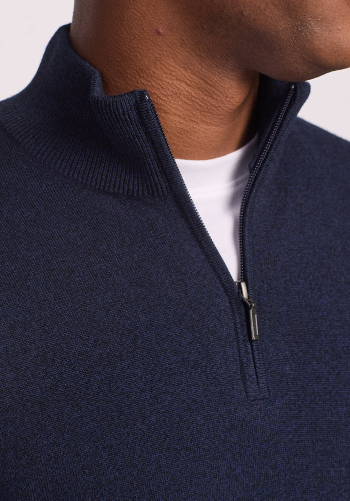 Close-up of a person wearing the Woolx Enzo Quarter Zip - Storm Cloud, a navy blue Merino wool sweater over a white T-shirt. The partially unzipped midweight layer reveals the tee, showcasing both comfort and style.