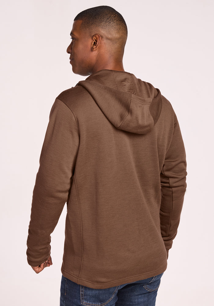 A man stands with his back to the camera wearing blue jeans and the Woolx Grizzly Sweatshirt in Bourbon Oak, set against a plain light background.