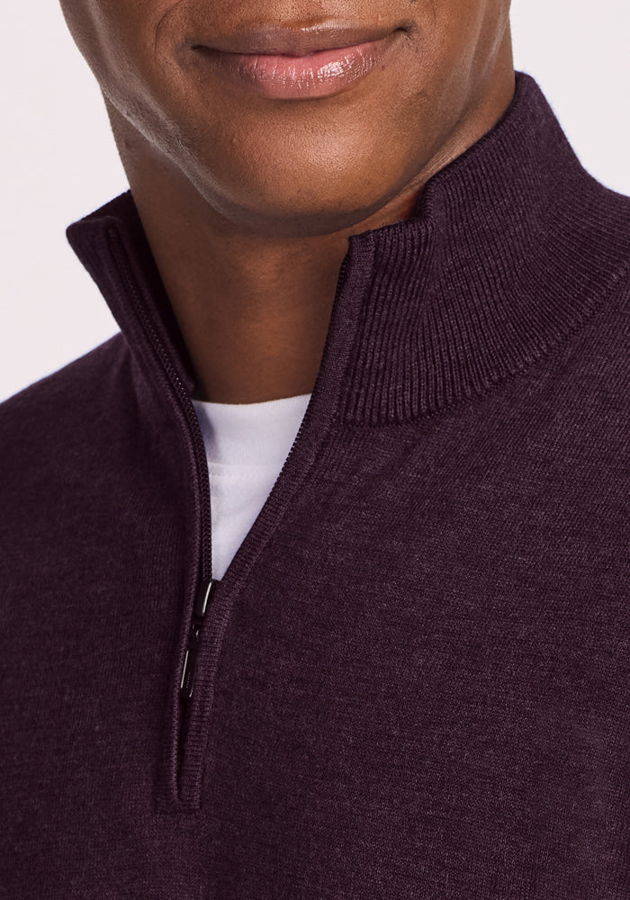 A close-up of a person wearing the Woolx Enzo Quarter Zip in Deep Plum over a white T-shirt, with the zipper partially open and only the lower half of their face visible.
