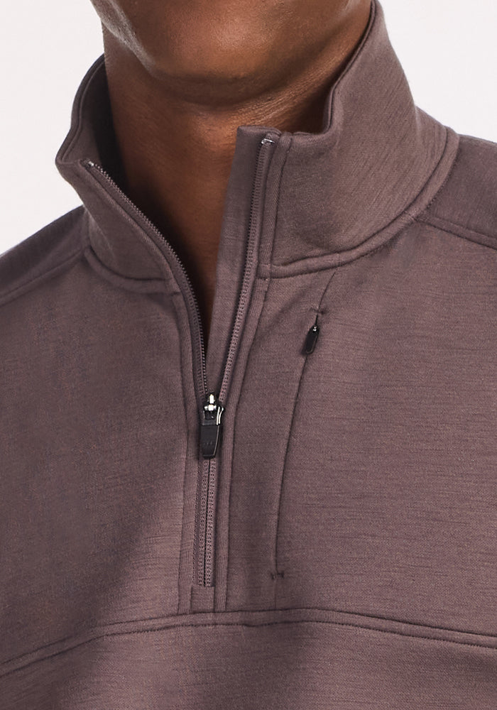 A close-up of a person wearing the Woolx Mason 1/4 Zip in Plum Truffle, featuring a high collar, partially unzipped neck, and visible Merino wool fabric texture and stitching details.
