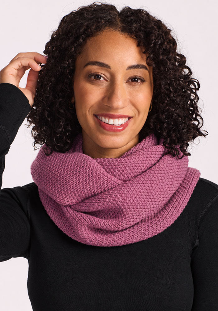 Smiling woman wears a Woolx Noelle Infinity Scarf in Toasted Rose and a black top against a plain light background.