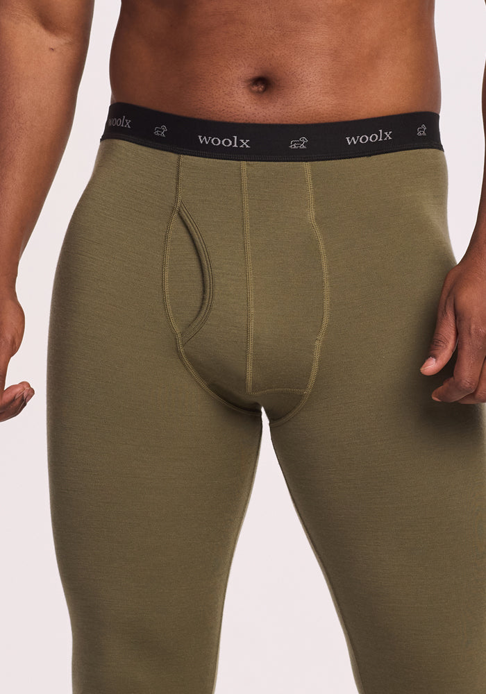 A person wears Woolx Backcountry Leggings in Winter Moss, featuring a black "woolx" waistband. Only the torso and upper legs are visible, with arms relaxed at their sides.