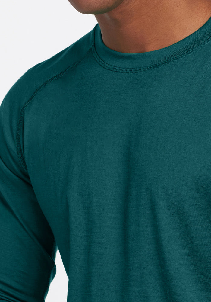 Close-up of a person wearing the Woolx Essential Tee in Riverbank Green, showing part of their neck, shoulder, and upper chest against a plain white background.