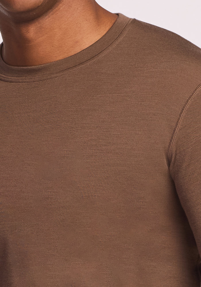 Close-up of a person wearing the Woolx Explorer Base Layer - Bourbon Oak, showing part of their neck, shoulder, and upper chest. The soft, smooth merino wool fabric stands out against a light background.