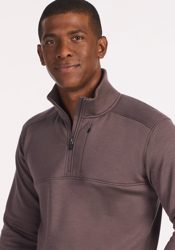 A man wearing the Woolx Mason 1/4 Zip in Plum Truffle stands against a plain light background, looking at the camera with a slight smile.