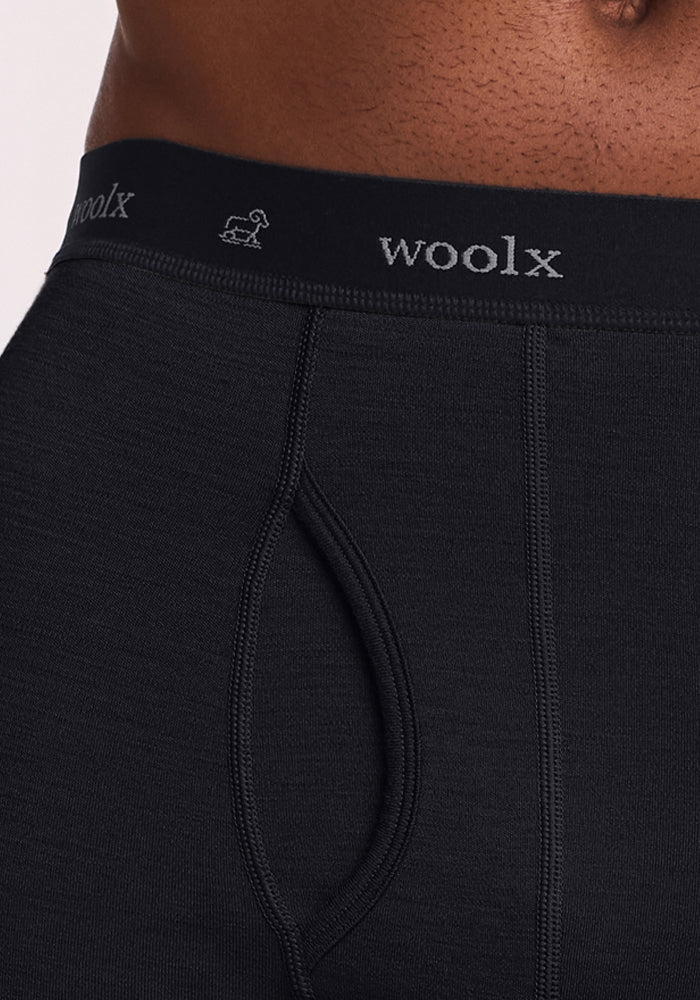 Close-up of a person wearing black Woolx Backcountry Leggings, featuring the Woolx logo on the waistband and visible stitching detail.