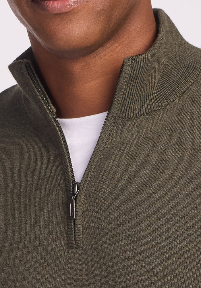 Close-up of a person wearing the Woolx Enzo Quarter Zip in Pine Needle over a white T-shirt. Only the lower face and upper torso are visible. The zipper is partially open, highlighting this ideal midweight layer.
