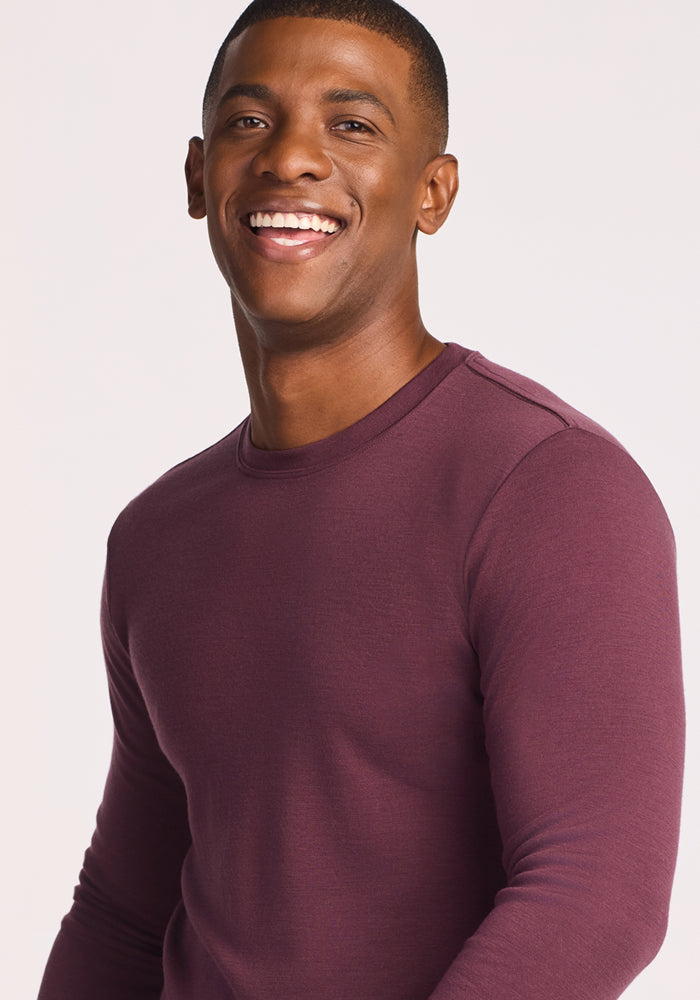 A smiling man wears the Woolx Easton Crew Neck Shirt in Grape Harvest, standing against a plain light background and looking at the camera.