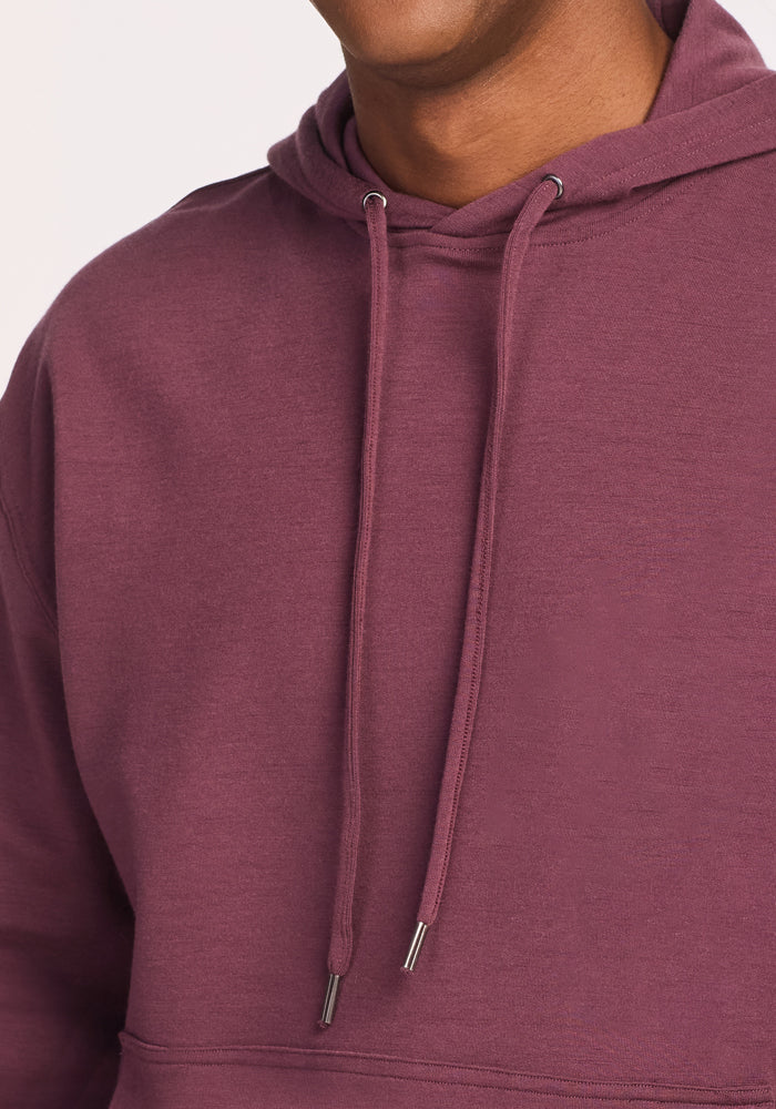 A person wearing the Woolx Chase Hoodie in Grape Harvest, shown from shoulders to upper chest with a partially visible face against a plain light background.