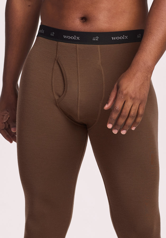 A person wears Woolx Backcountry Leggings in Bourbon Oak, featuring a black elastic waistband with "woolx" in white text. Only the torso and upper legs are visible.