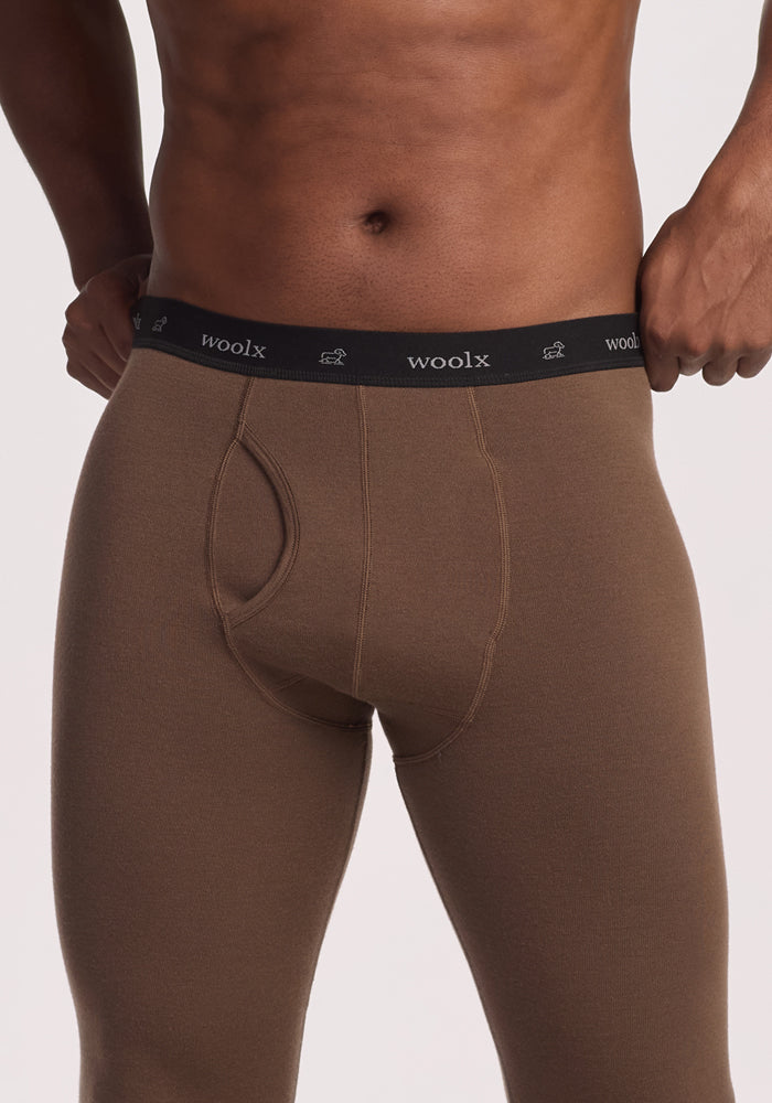 A close-up of a person wearing Woolx Arctic Leggings - Bourbon Oak, an ultra-heavyweight Merino wool base layer, showing the branded black waistband. The torso and upper legs are visible against a neutral background.