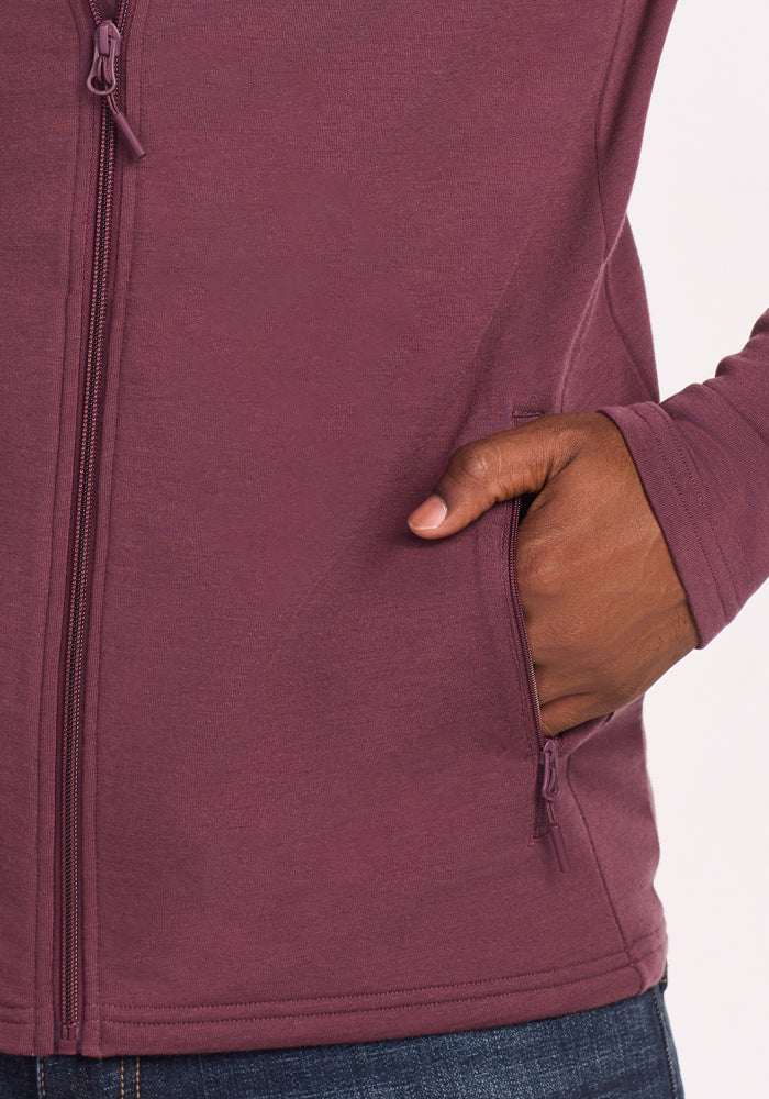 A person wearing the Woolx Boulder Hoodie - Grape Harvest with their right hand in the side pocket. The bottom of this breathable hoodie and part of blue jeans are visible.