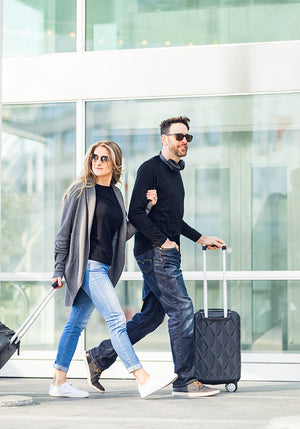 Man & Women with luggage walking through airport wearing Woolx