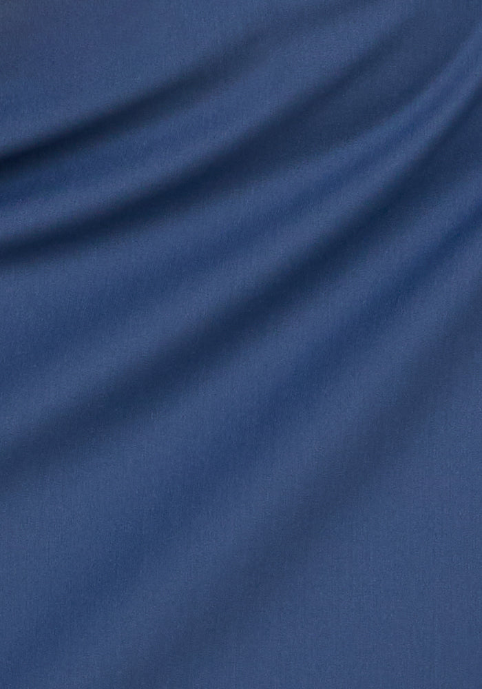 Close-up of smooth, vintage indigo fabric with subtle diagonal folds and soft shadows, showcasing the texture and movement of the Woolx Topanga Skort—ideal moisture-wicking activewear for women.